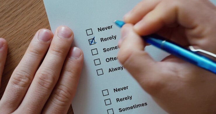 Primo piano di una mano che segna le risposte su un modulo di sondaggio stampato con opzioni come mai, spesso e sempre. Concetto di questionari, feedback, valutazione e raccolta dati.