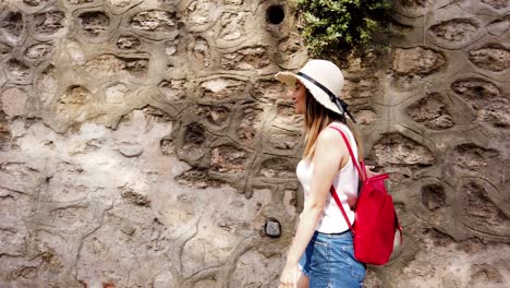 slow motion:beautiful young girl touches wall while walking on the street