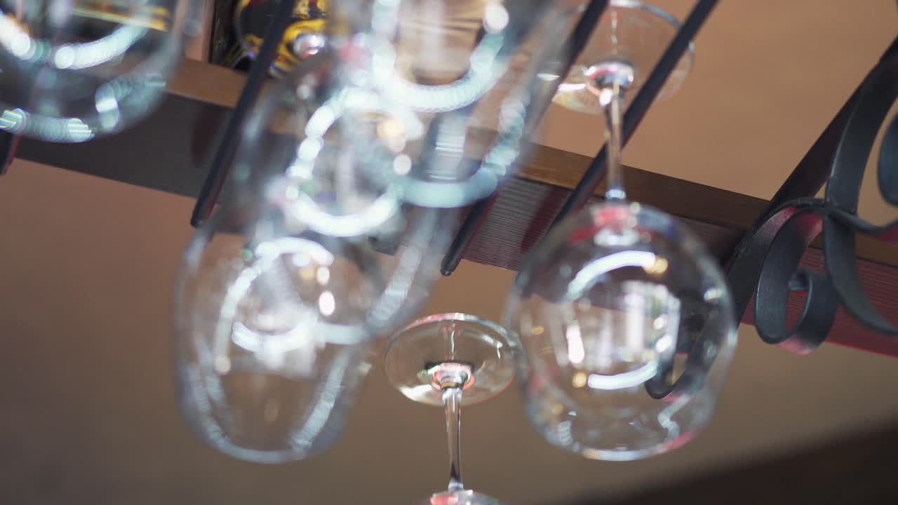 Clean brilliant glasses are placing into special rack by somebodies hand with white cloth in the restaurant. Closeup