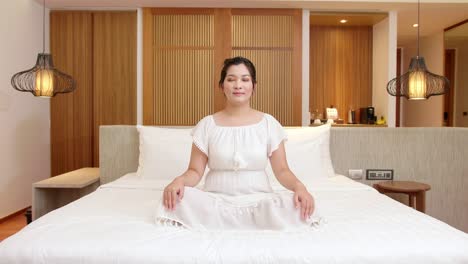 Asiatische-Frau-übt-Während-Ihrer-Entspannungszeit-Meditation-Auf-Ihrem-Schlafzimmerbett,-Um-Ihren-Geist-Zu-Beruhigen