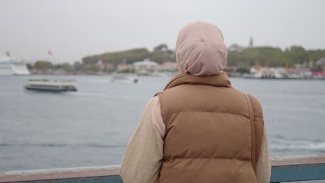 woman in hijab looking out at the sea in istanbul