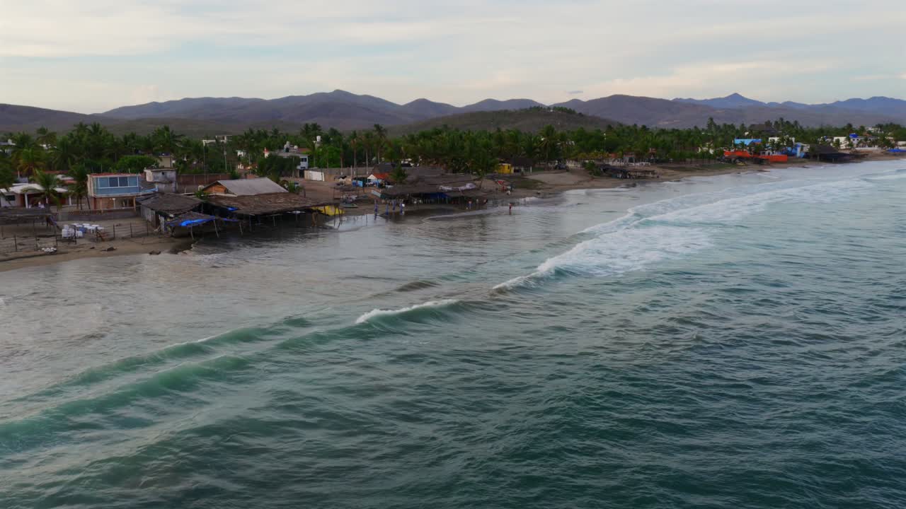 Stunning aerial footage captures Punta Perula's serene beachfront in Jalisco, Mexico, where gentle waves meet a lively shore under soft, ambient lighting. Perfect for travel inspirations