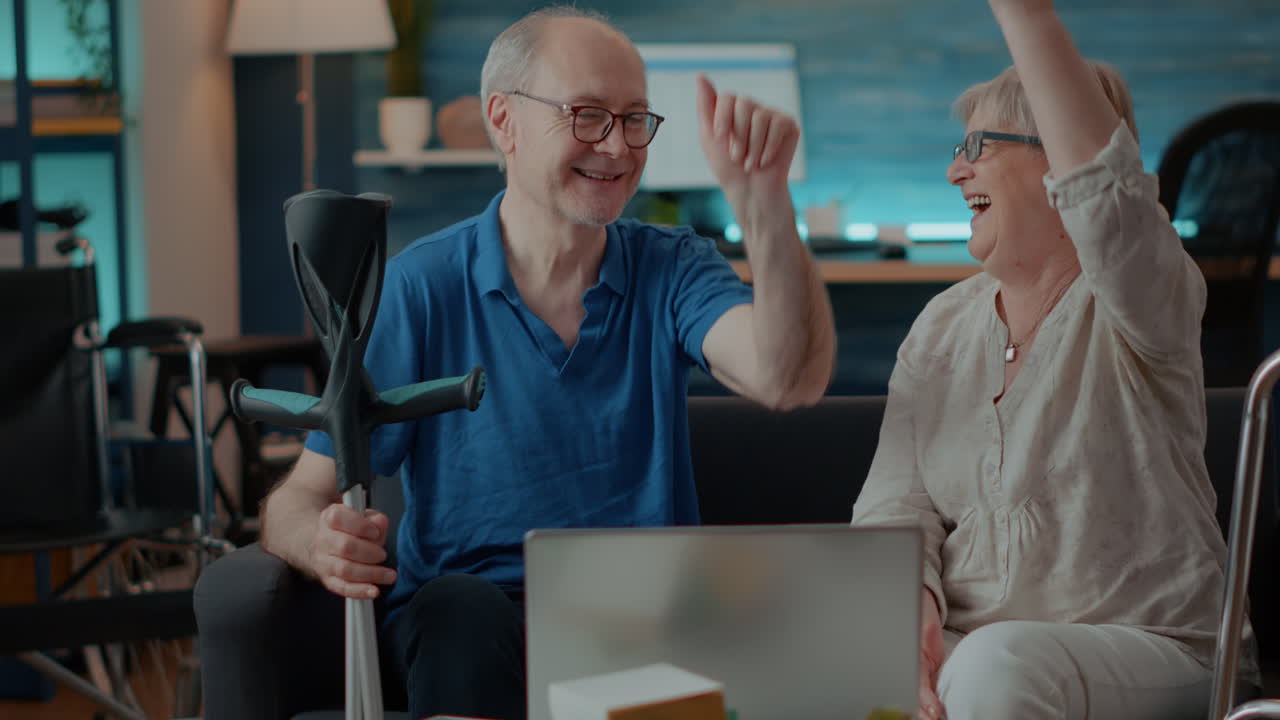 Senior Couple Using Laptop with Crutches and Wheelchair