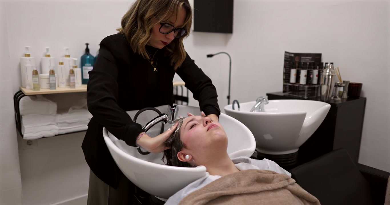 Parrucchiere professionista che lava i capelli del cliente nel lavatesta del salone
