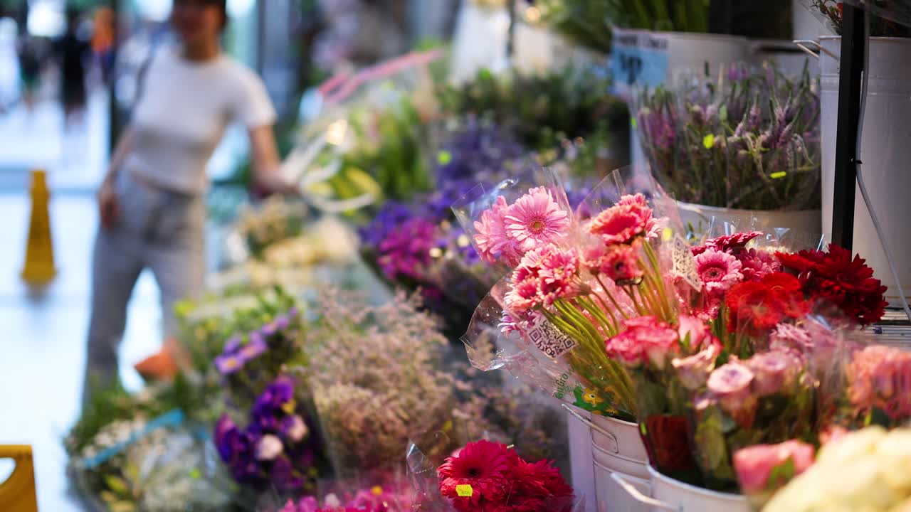 다채로운 꽃이 전시되어 있고, 사람들이 지나가고 있습니다.