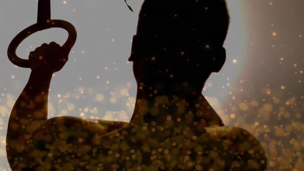 황금빛으로 빛나는 반점이 운동하는 사람의 실루 ⁇ 에 대해 움직이는 디지털 복합 비디오