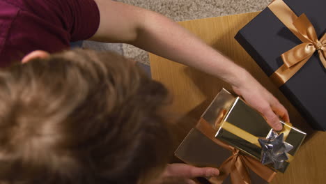 overhead shot of man picking up wrapped gifts or presents from table at home