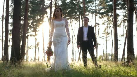 bride and groom walking through a sunny forest
