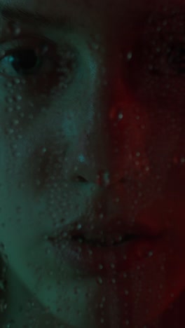 close-up portrait of a woman with water droplets and neon lighting