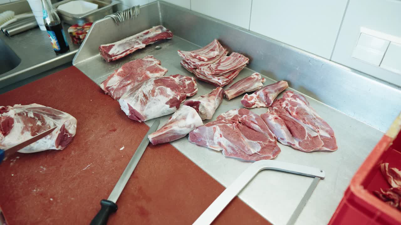 macellaio che taglia con cura la carne di agnello sul banco da lavoro indossando guanti da macellaio e mettendoli in ordine di taglio