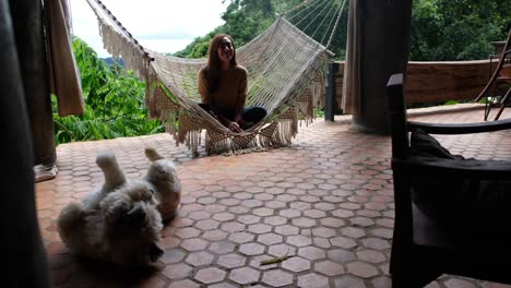 una joven asiática sentada en una hamaca y mirando a un perro