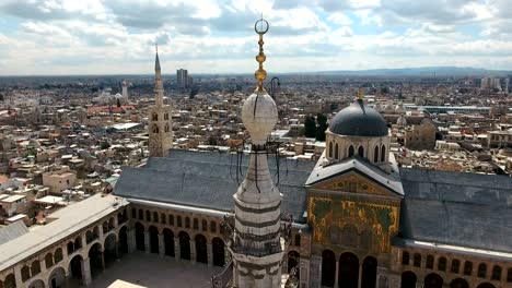 aerial view around the minaret of the umayyad mosque in syria. drone is flying around the minaret with the city of damascus in the background.