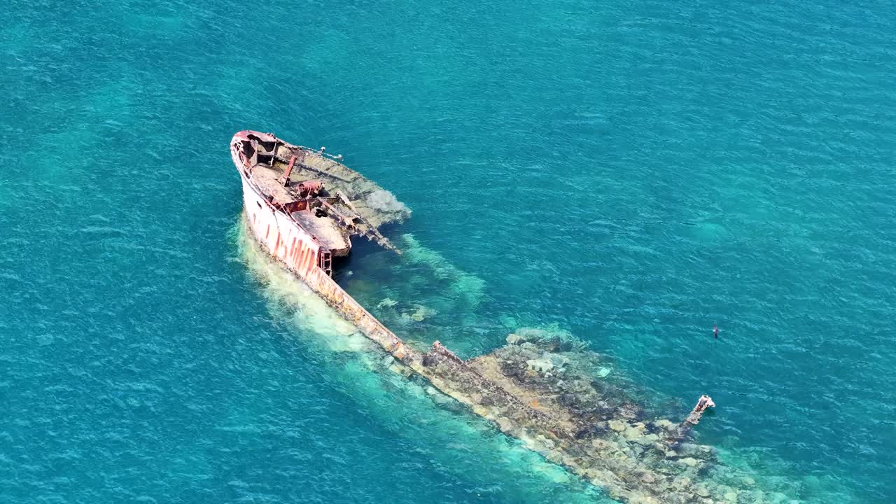 Ripresa aerea dall'alto di un relitto arrugginito in limpide acque turchesi dell'Oceano Pacifico.