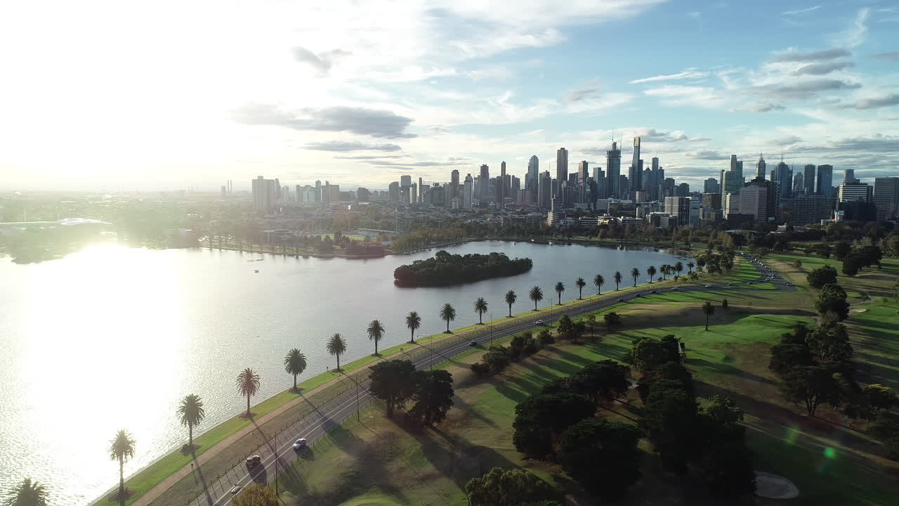 Dolce discesa che rivela il Lago Albert Park con il traffico dell'ora di punta pomeridiana che si muove in fila indiana dal CBD verso i sobborghi