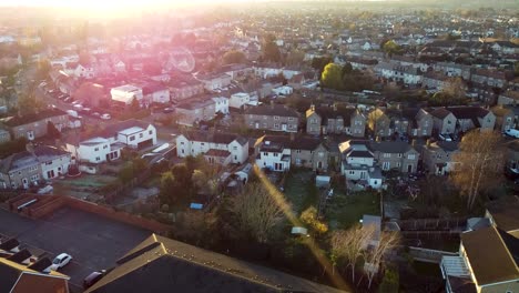 sunset strikes with flare in london suburb area, aerial shot during golden hour