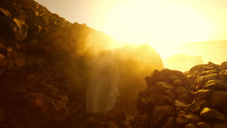 powerful ocean waves at sunrise/sunset over volcanic rocks