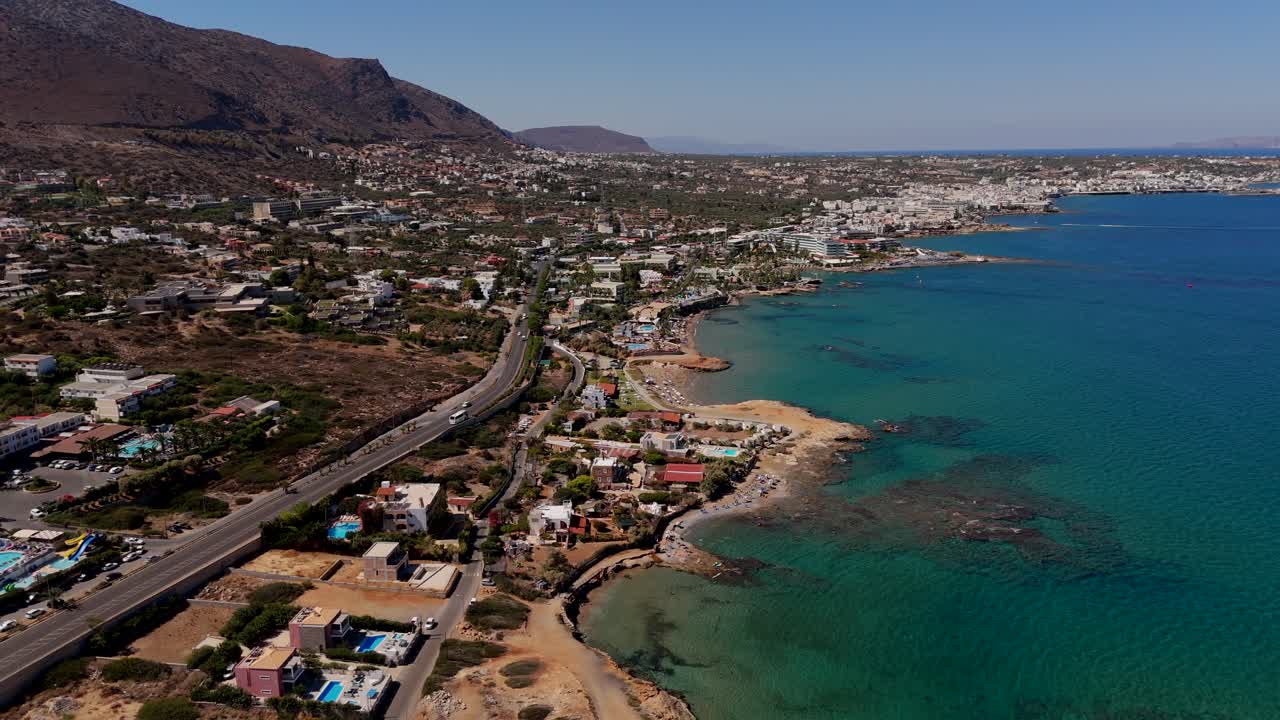 Aerial view of hotels, a winding road, and beach along Crete Island, Greece.