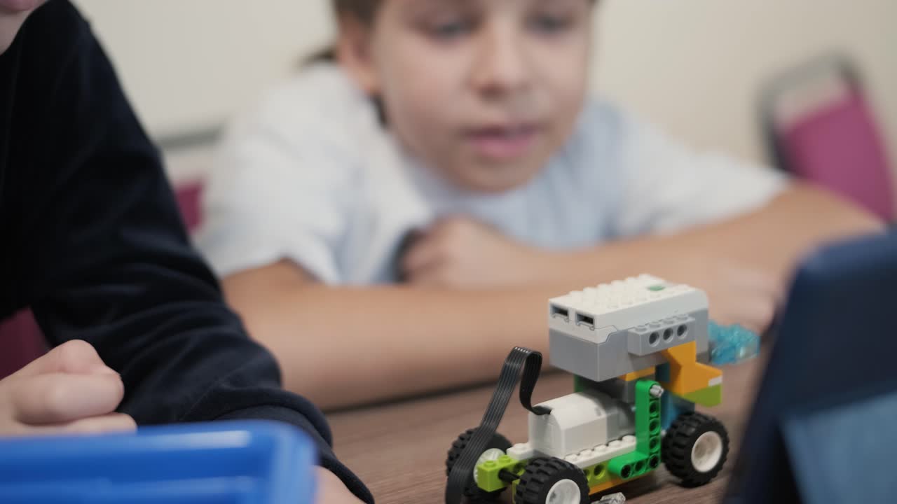 los niños participan en actividades de aprendizaje básico, montando kits de robótica con enfoque y trabajo en equipo en un entorno de aula