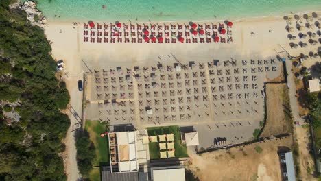 Drone-flying-over-a-beach-with-beach-chairs-and-people-enjoying-the-sun