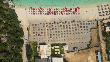 Drohne-Fliegt-über-Einen-Strand-Mit-Liegestühlen-Und-Menschen,-Die-Die-Sonne-Genießen