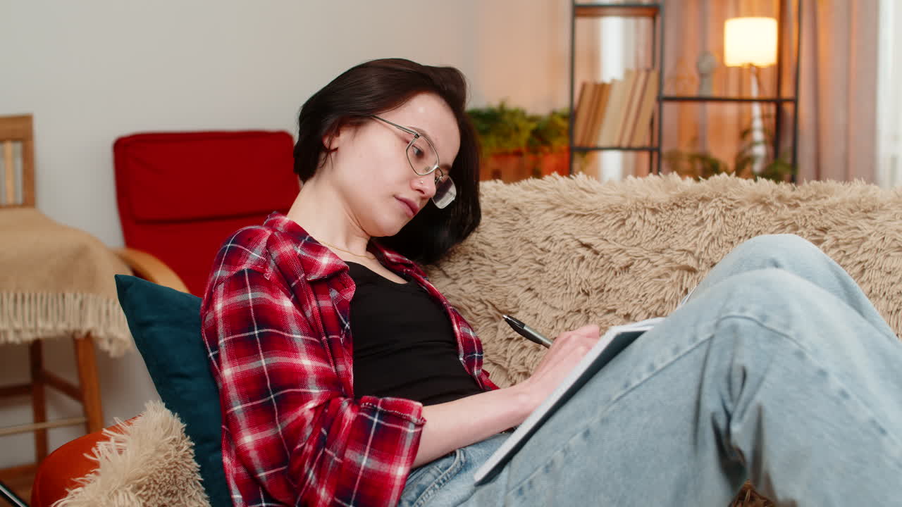 Young woman sketching in notebook at home focused and inspired by creative process with calm energy