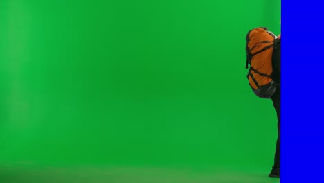 man hiking with a large orange backpack on a green screen