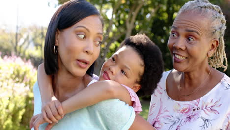 smiling african american family enjoying outdoor time, child hugging mother while grandmother watche