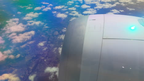 vista aérea desde la ventana de un avión, que muestra el motor de la aeronave y una vasta extensión de nubes y tierra debajo