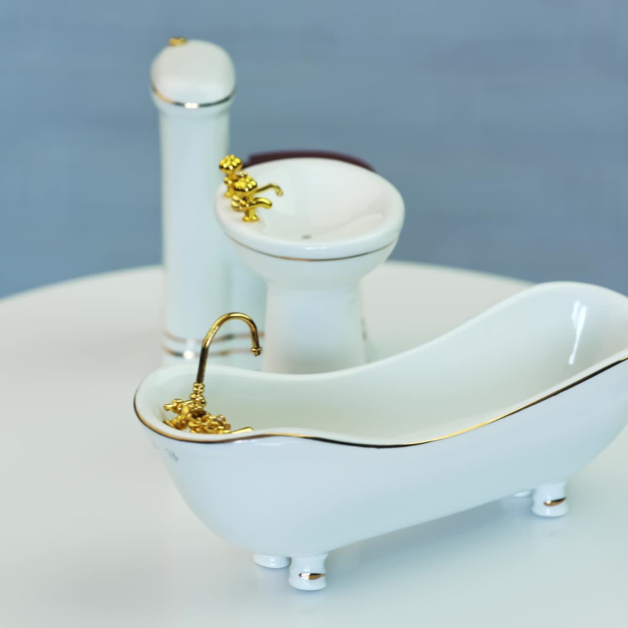 White plumbing for doll's house bathroom. Miniature sanitary engineering with golden appliances. Close up