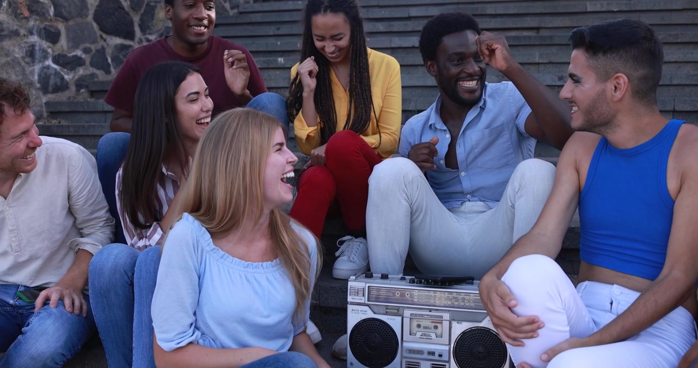 Felici giovani amici di diverse origini che ridono e ascoltano musica all'aperto