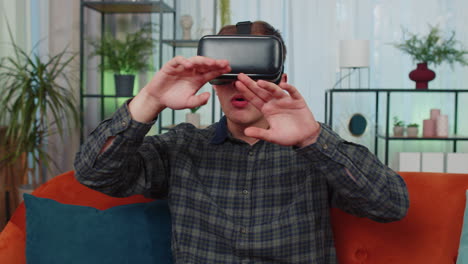 Un-Joven-Usa-Gafas-De-Realidad-Virtual-En-Casa,-Disfrutando-Del-Concepto-De-Vídeo-Moviendo-Las-Manos-En-El-Aire