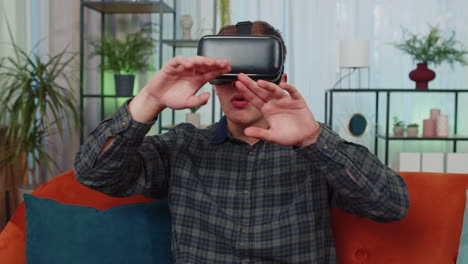 joven usa gafas de realidad virtual en casa, disfrutando del concepto de video moviendo las manos en el aire