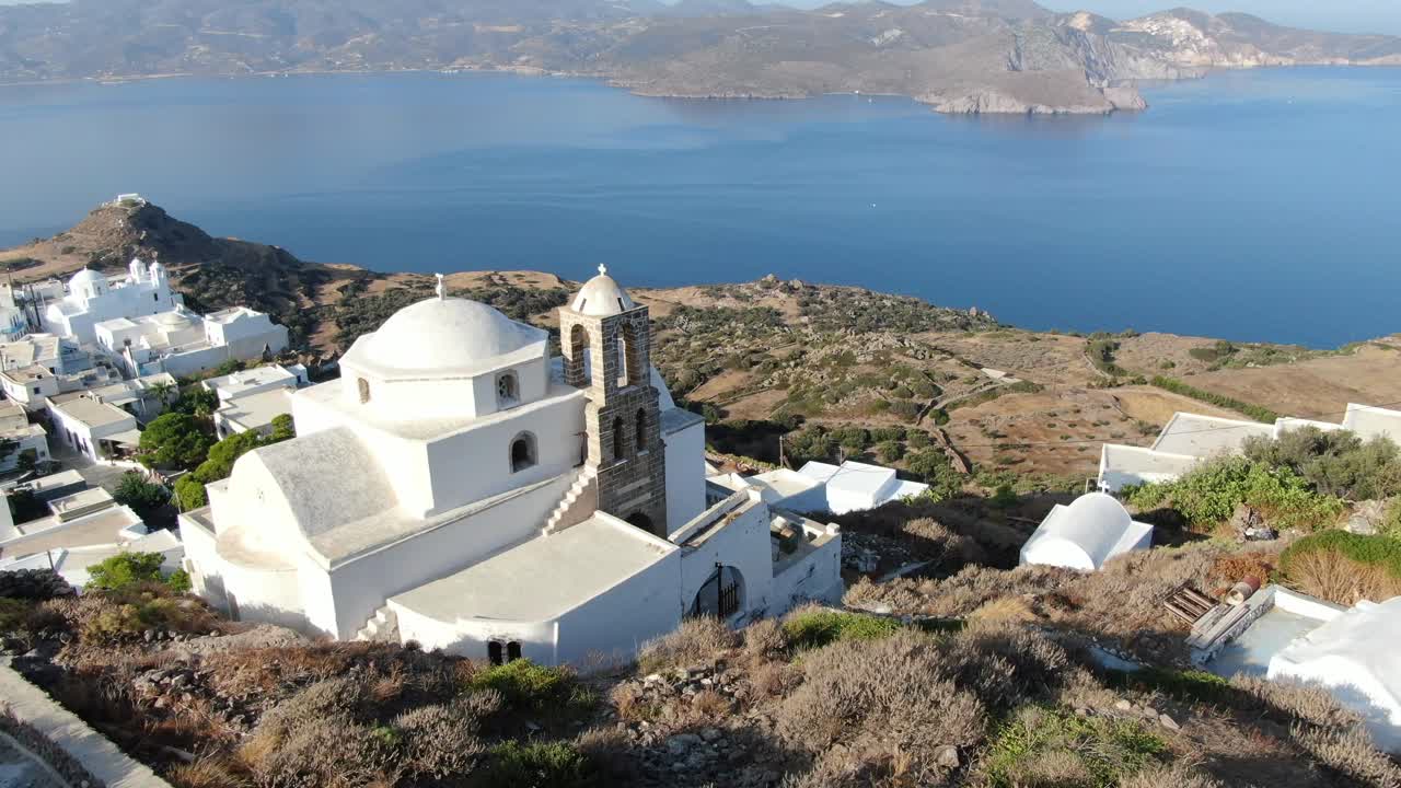 vista de avión no tripulado en grecia volando sobre una iglesia blanca en una colina con una casa blanca griega ciudad frente al mar azul en una montaña