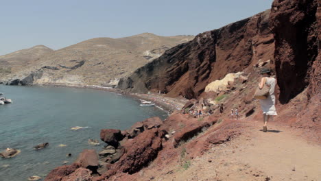 A-woman-follows-the-path-that-leads-to-the-red-beach-that-is-visible-in-the-background