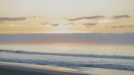 Lapso-De-Tiempo-Del-Amanecer-Tropical-Con-Olas-Rompientes-Y-Paisaje-Nublado-En-El-Fondo