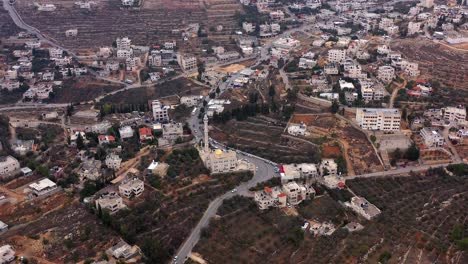 aerial view of a middle eastern town with a mosque and terraced fields