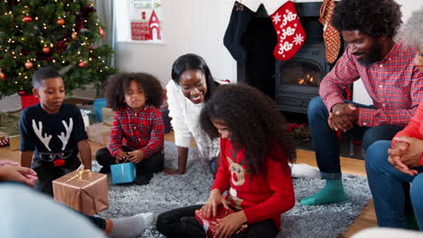 daughter opening gift as multi generation family celebrate christmas at home together