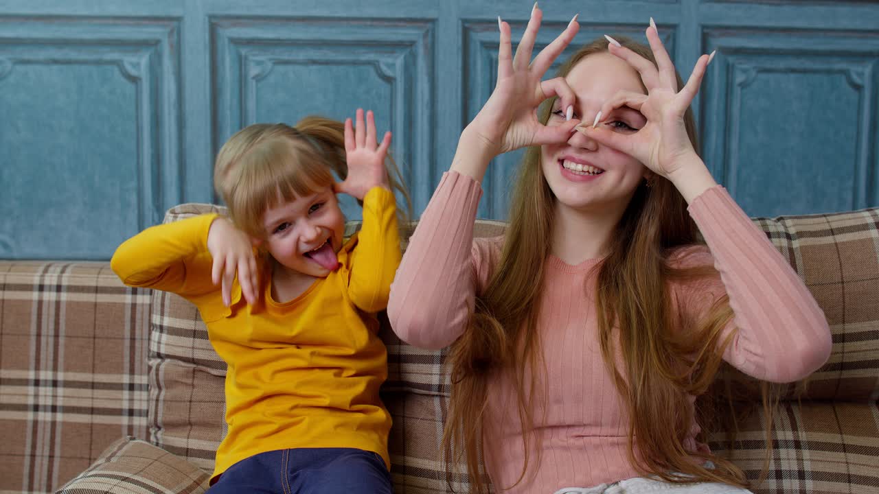 재미있는 젊은 어머니와 딸은 재미있는 얼굴을 하고 집에서 셀피를 찍고 재미있는 활동을 즐기고 있습니다.