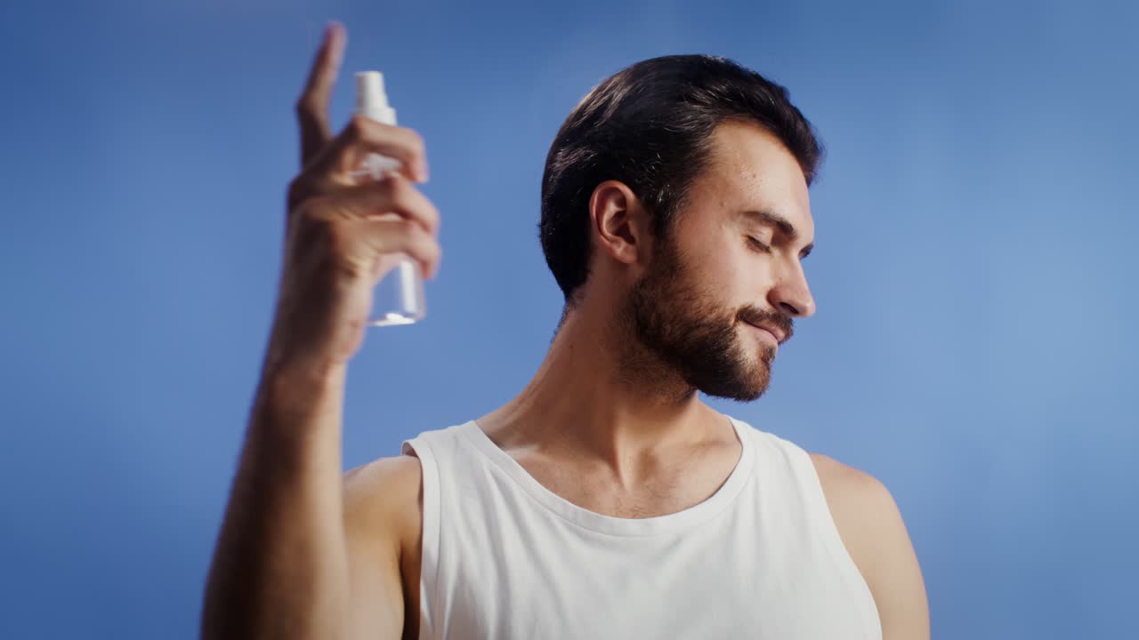 Man spraying cologne on face