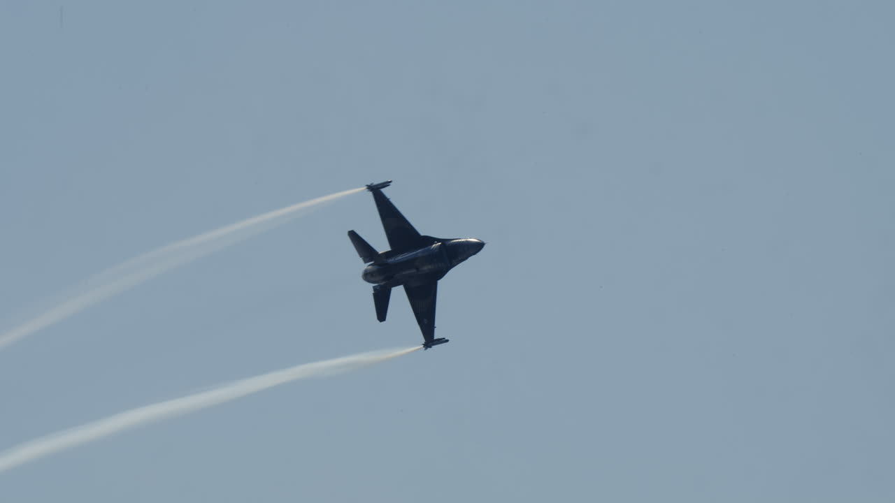 F-16 Kampfjet fliegt und hinterlässt Kondensstreifen am klaren blauen Himmel