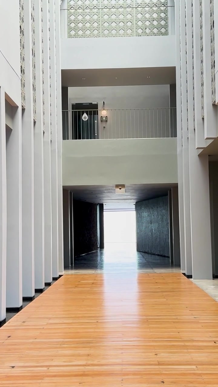 Um corredor de entrada de resort elegante e moderno em Phuket, Tailândia, com colunas altas, paredes de vidro e iluminação natural