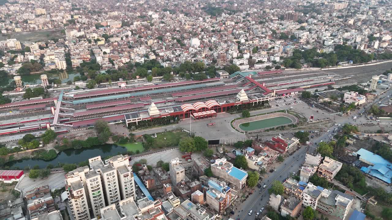 A sprawling railway terminal integrated into the urban fabric, surrounded by road networks, green patches, and high-rise apartments
