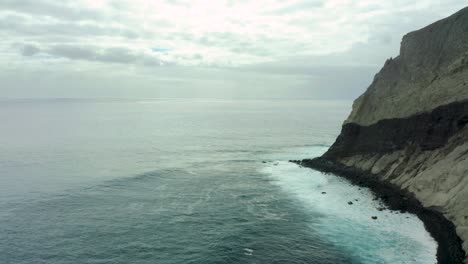 Steep-rocky-cliffs-drop-off-into-coastal-waters-on-overcast-day,-San-Benedicto-Revillagigedo-Islands-Mexico