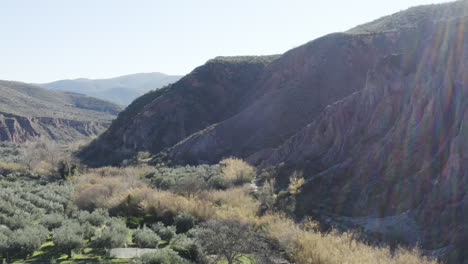 dramatic rocky mountain valley with lush green foliage and sun flare