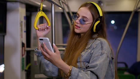 young girl using mobile phone internet social network listening music traveling by public city bus