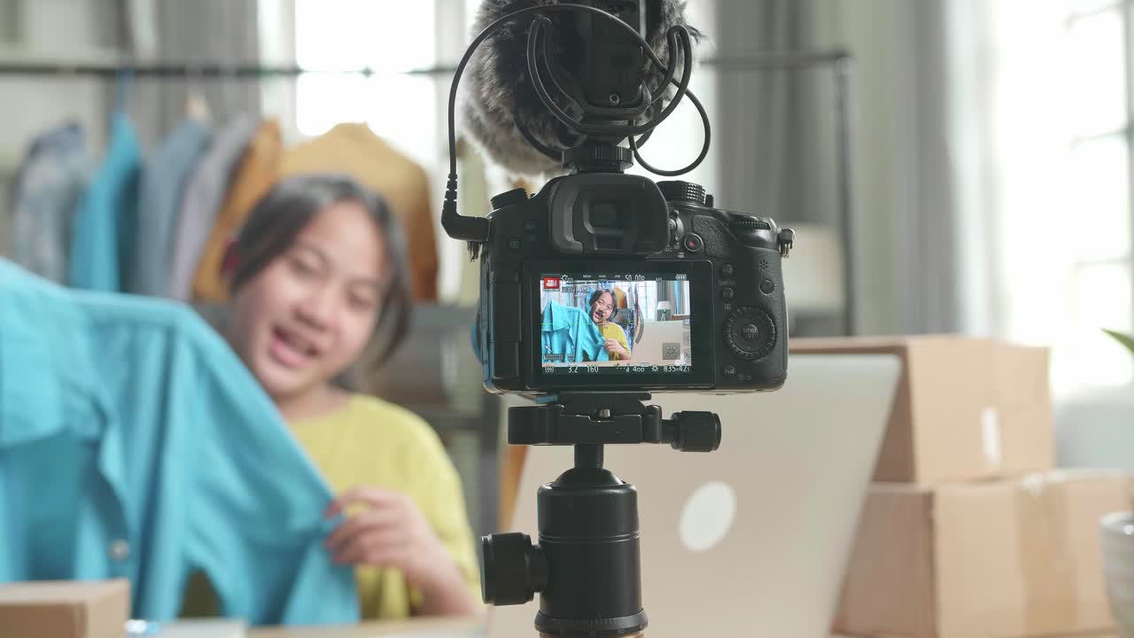 Camera Monitor Recording Asian Young Girl Online Seller Recommending A Shirt While Using Computer For Selling Clothes At Home
