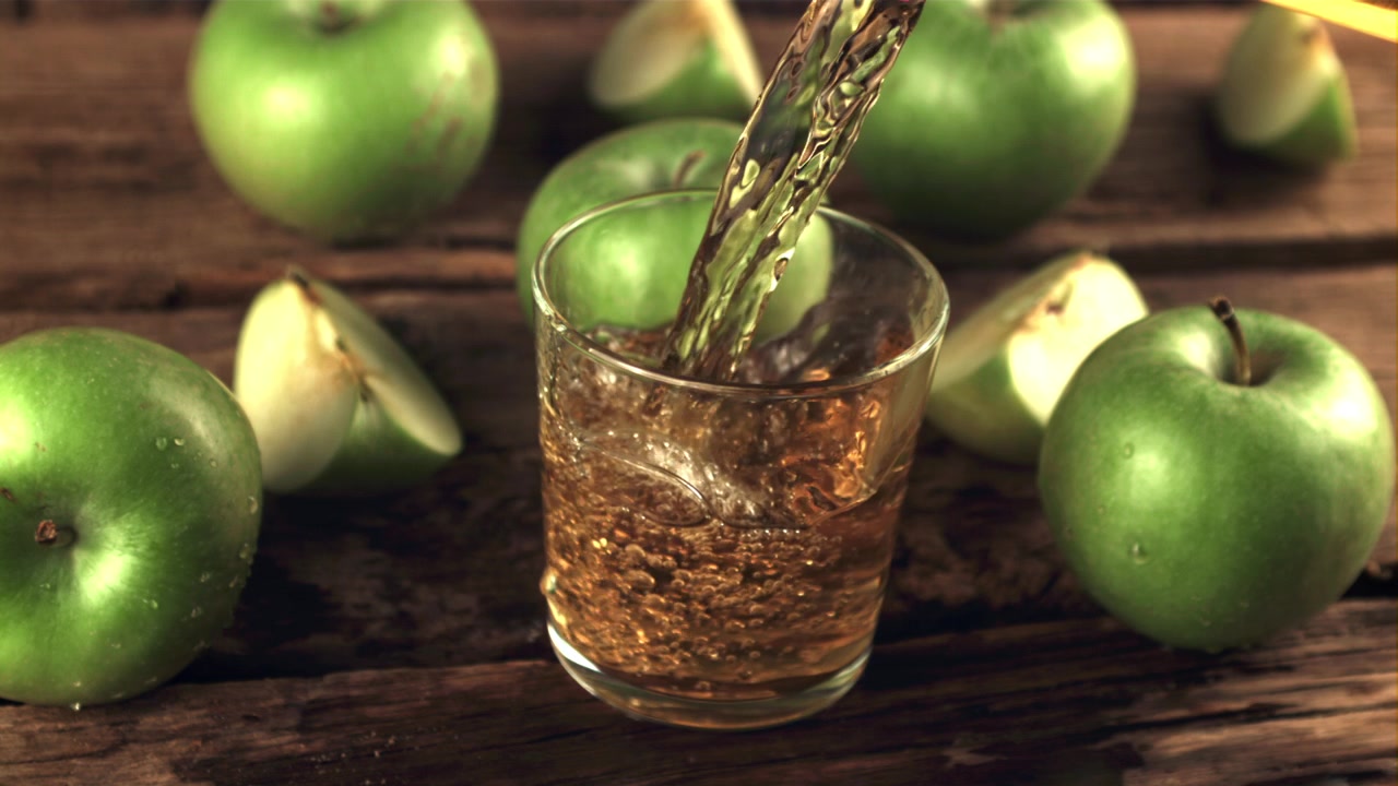 Succo fresco di mela verde versato in un bicchiere su un tavolo di legno