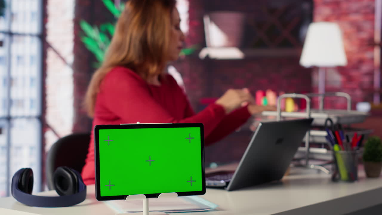 Woman working at desk with tablet green screen