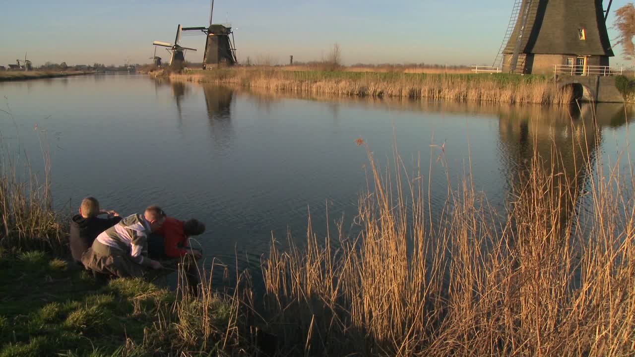 아이들은 네덜란드의 운하를 따라 풍차 앞에서 논다