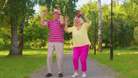 Senior-stylish-couple-grandmother-grandfather-dancing,-listening-music-on-musical-speakers-in-park